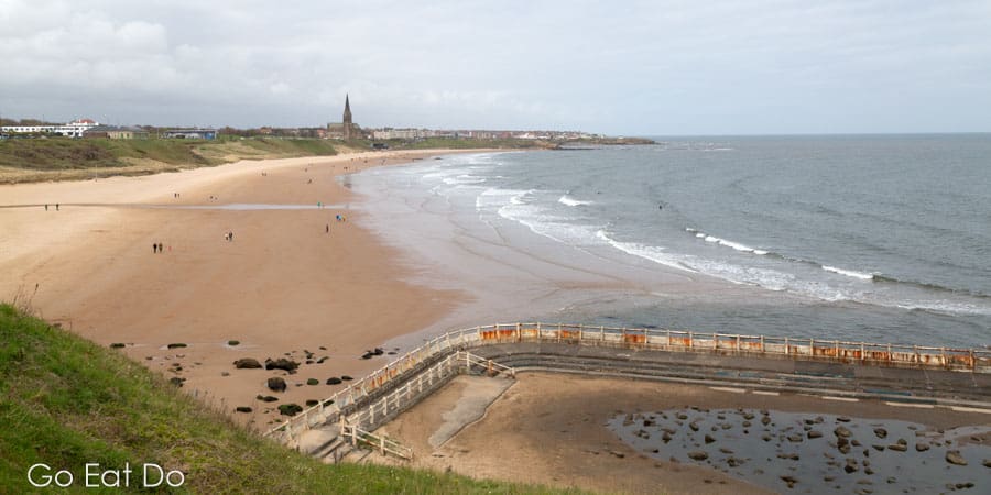 Tynemouth pool and the golden sands of the beach seen from the Seasider oped-topped bus in North East England