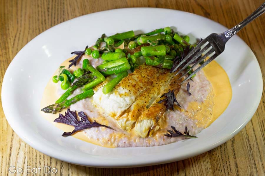 Grits served with seasoned flounder, asparagus, peas, spring onion and tomato cream.