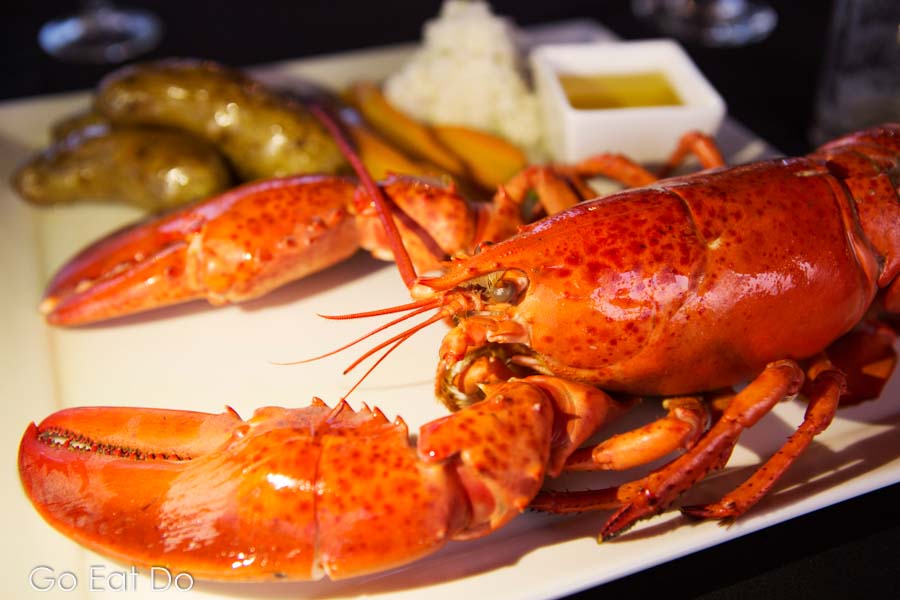 Lobster on a dinner plate, served with fresh vegetables and butter sauce, in Pictou, Nova Scotia