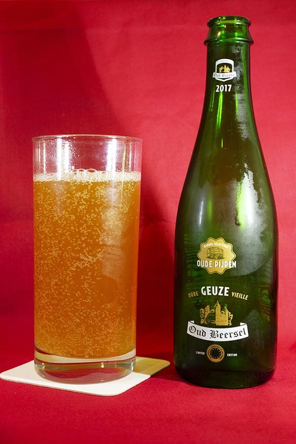 Glass of Oude Beersel's Oude Pijpen 2017 Oude Geuze beer, a limited edition bottle-conditioned lambic beer matured in port wine barrels