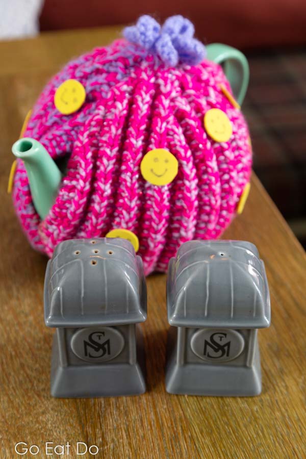 Teapot with a colourful wool tea cosy and salt and pepper pots with the St Mary's Inn logo