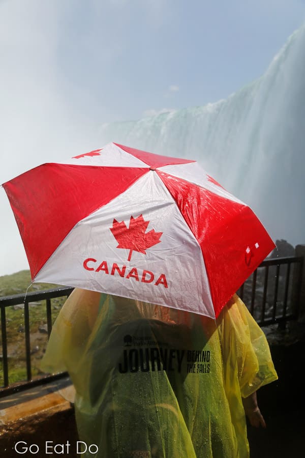 Woman with a Canada umbrella viwing Horseshoe Falls at the Journey Behind The Falls observation platform in Niagara Falls, Ontario, Canada