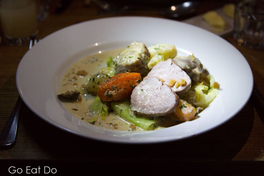 A plate of pork stewed with winter vegetables. The dish features carrots, shallots and a creamy sauce.