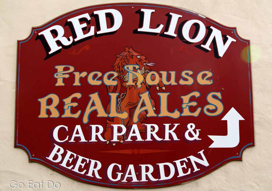 Sign for the Red Lion Free House in Wiltshire, England, pointing to the car park and beer garden.