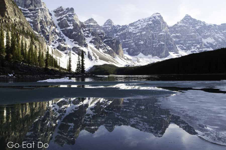 Craggy, snowy peaks of the Canadian Rockies on the surface of Moraine Lake at Banff National Park in Alberta, Canada