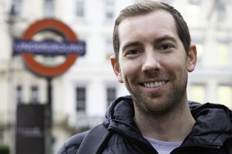 Smiling face of Rich McCor, the Instagram star known as Paperboyo, by a London Underground sign