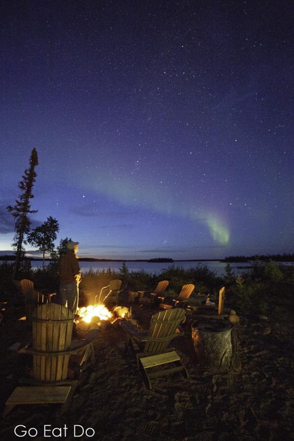 Northern Lights in the night sky above a camp fire at Gangler's North Seal Wilderness Adventure Lodge in northern Manitoba, Canada