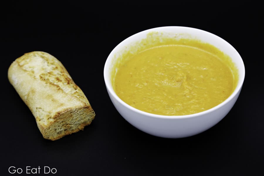 Freshly baked baguette next to a bowl of easy-to-make lightly spiced butternut squash soup