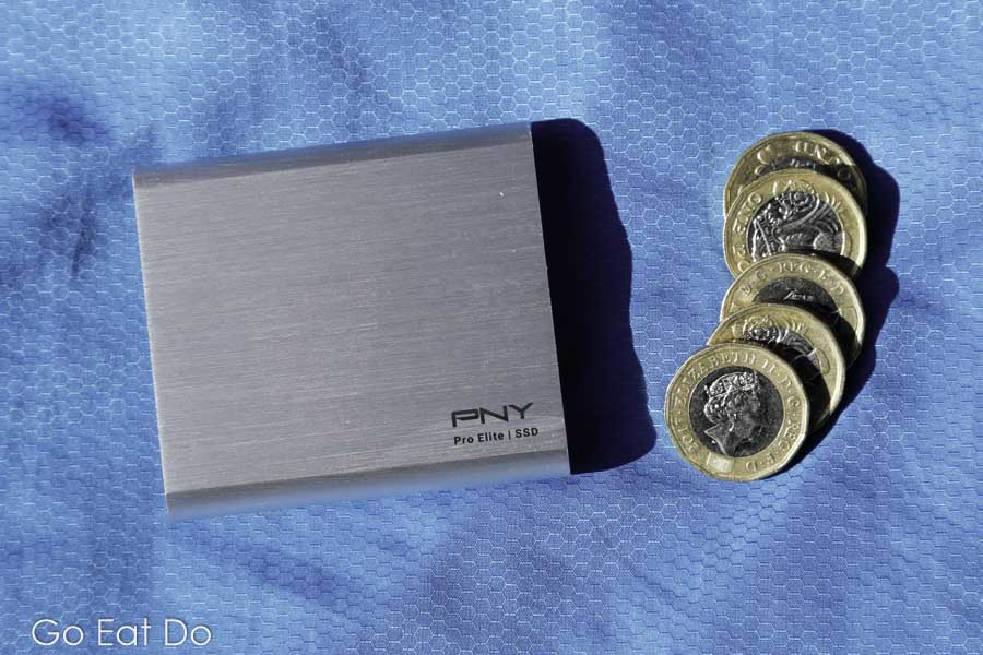 PNY Portable SSD Pro Elite hard drive with a cable next to five pound coins for scale