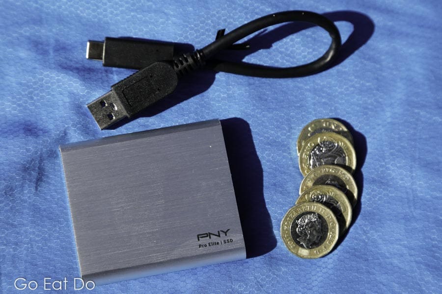 PNY Portable SSD Pro Elite hard drive with a cable and pound coins for scale
