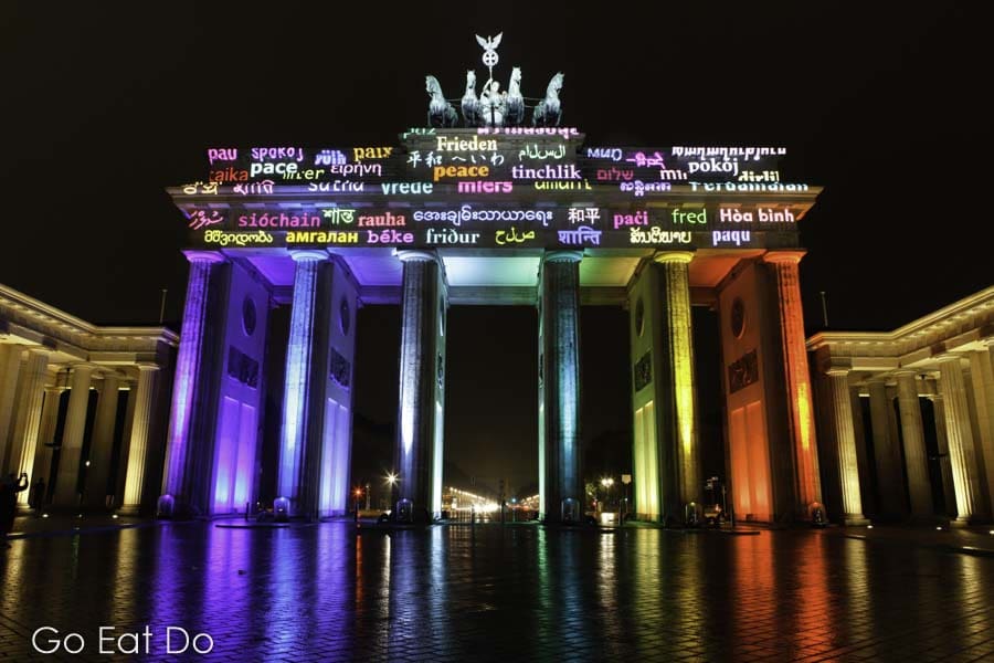 The word for peace, in multiple languages, projected onto the Brandenburg Gate in Berlin, Germany.