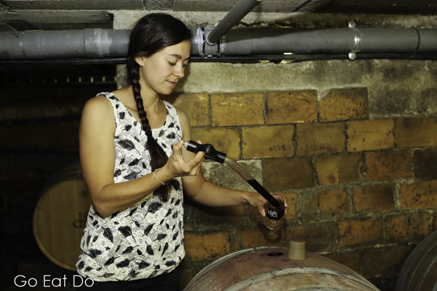 Woman tests wine from a barrel in the cellar of the Domaine de Massereau winery in Sommieres, France