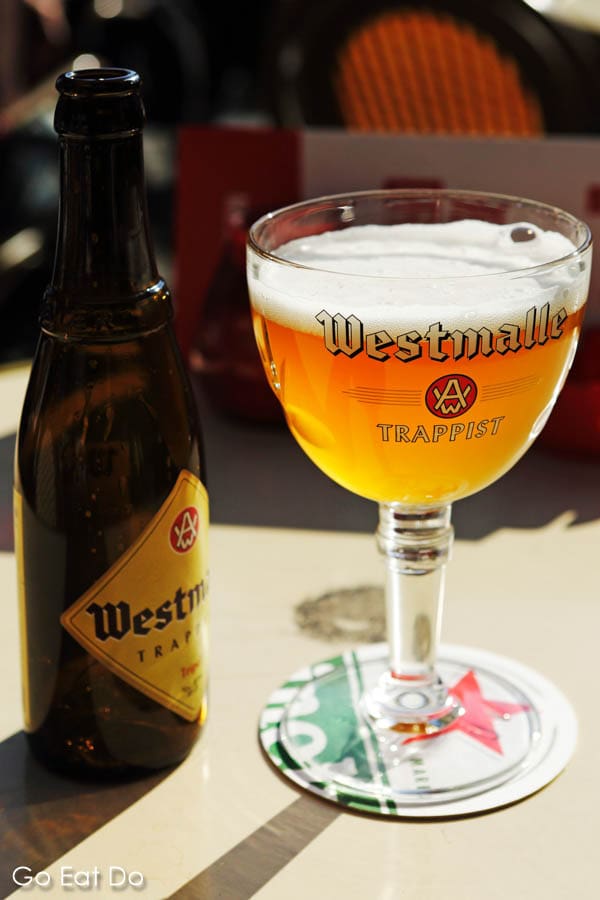 Bottle of Westmalle Tripel served in a goblet glass.