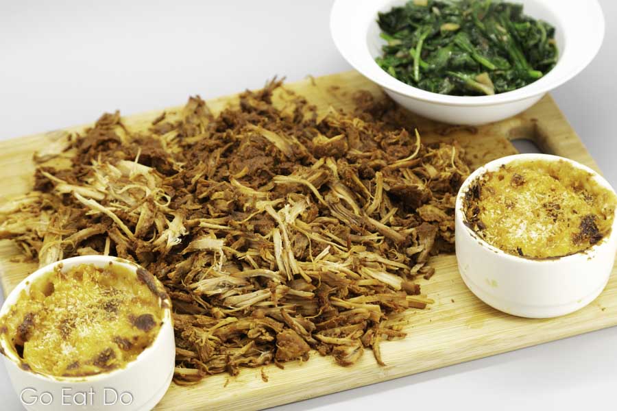 Home-cooked pulled pork served shredded with mac and cheese and wilted spinach