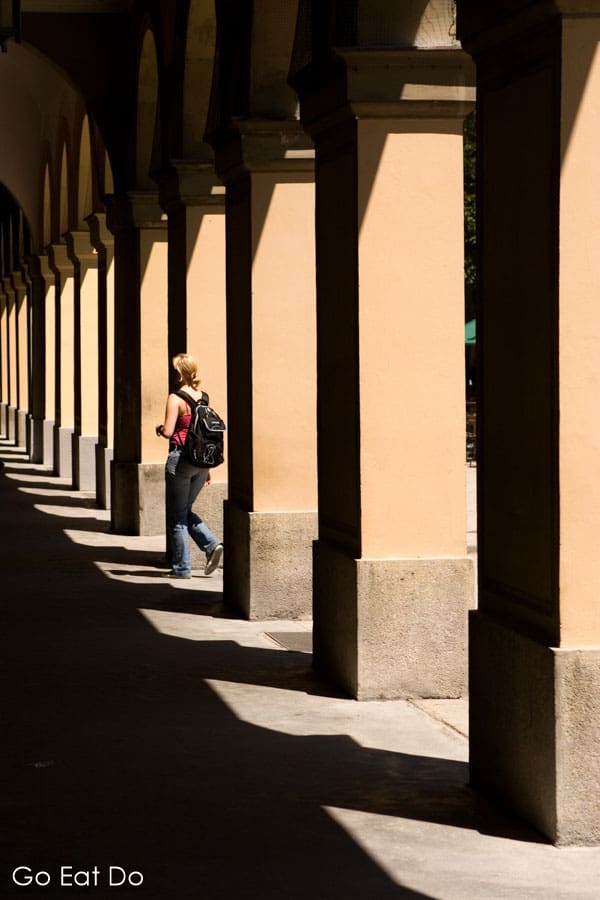 A woman walks along the corridor between pillars of the Hofgarten in Munich, Germany
