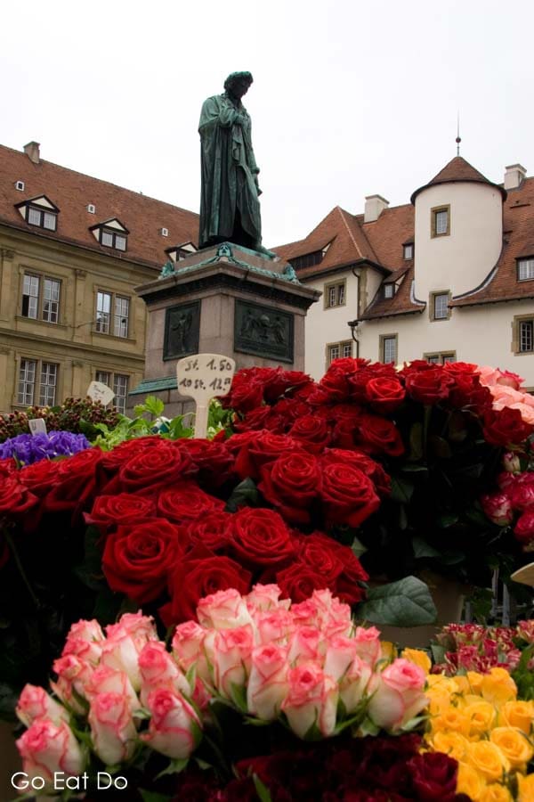 Flowers under the statue of Friedrich Schiller on market day in Stuttgart, Germany