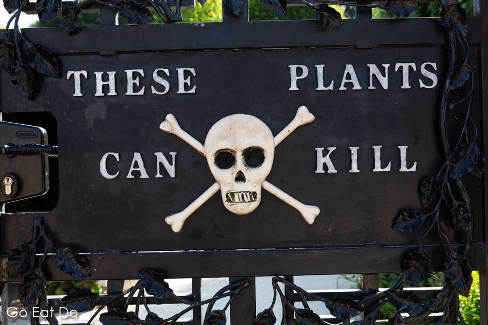 Skull and crossbones sign warning that 'these plants can kill' on the locked gate of the Poison Garden at Alnwick Garden in Northumberland, England