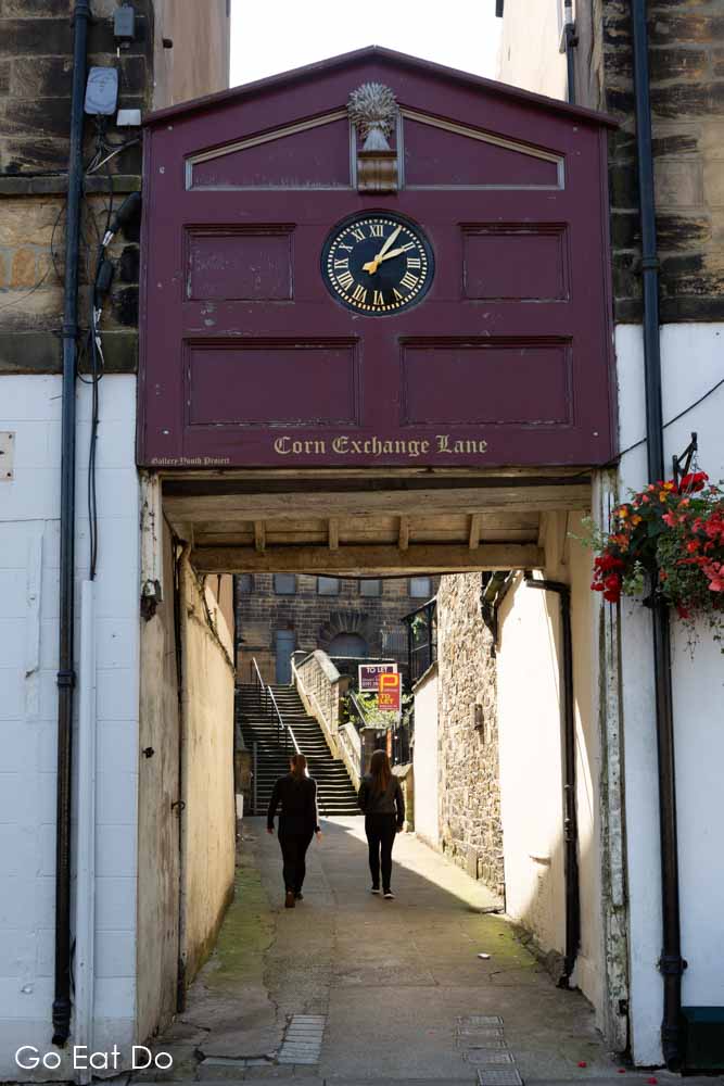 People walking along Corn Exchange Lane, which has a clock at its entrance, in Alnwick, Northumberland