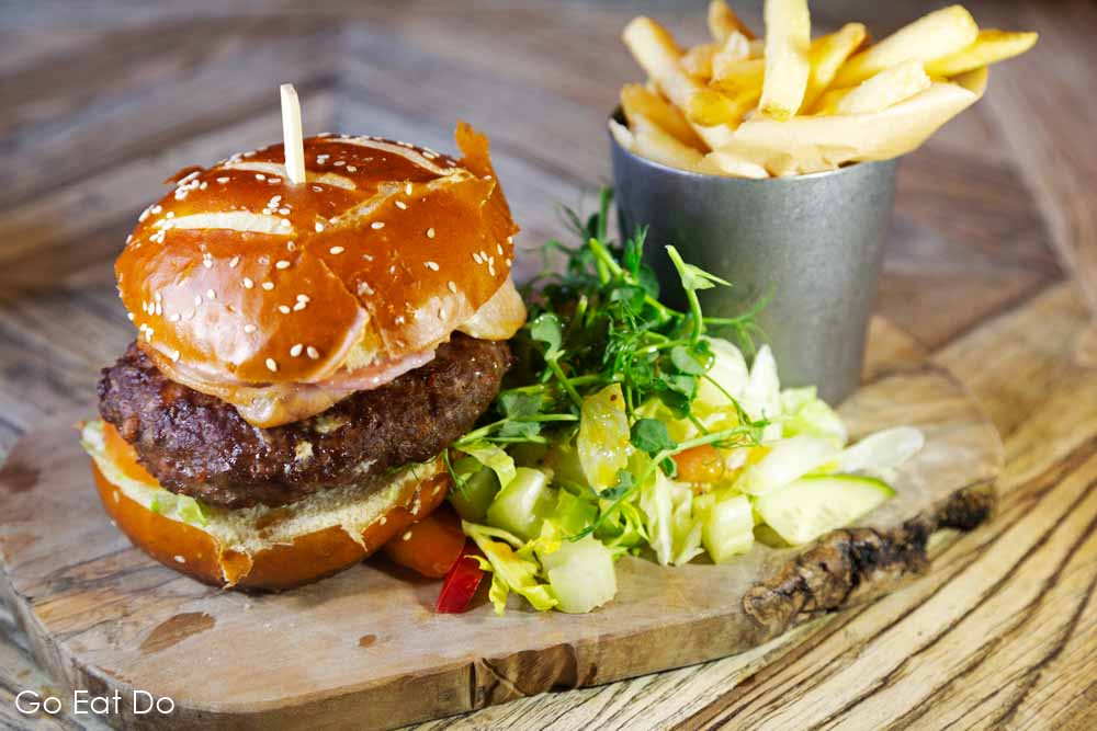 Burger served for lunch with fries on a wooden board at The Cookie Jar in Alnwick, Northumberland
