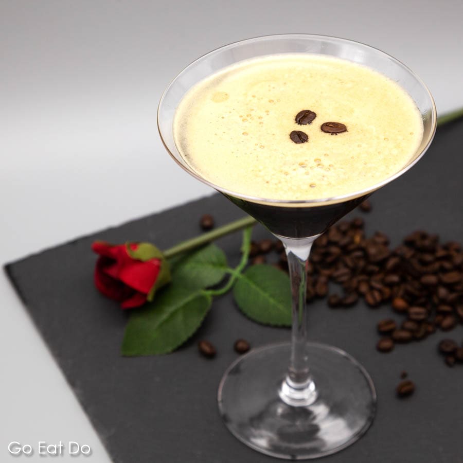 Espresso martini served in a martini glass, garnished with roast coffee bean and presented with a rose.