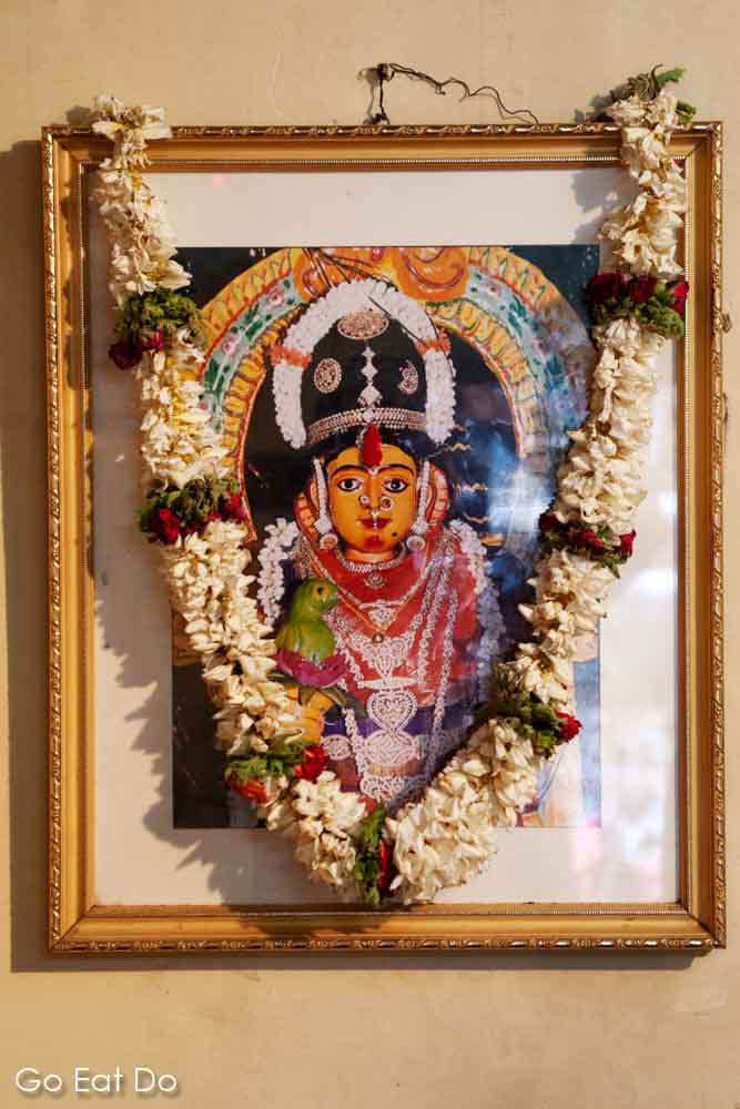 Garlands hang on a picture of the Hindu goddess Draupadi (Drowpathy) in Bengaluru, India