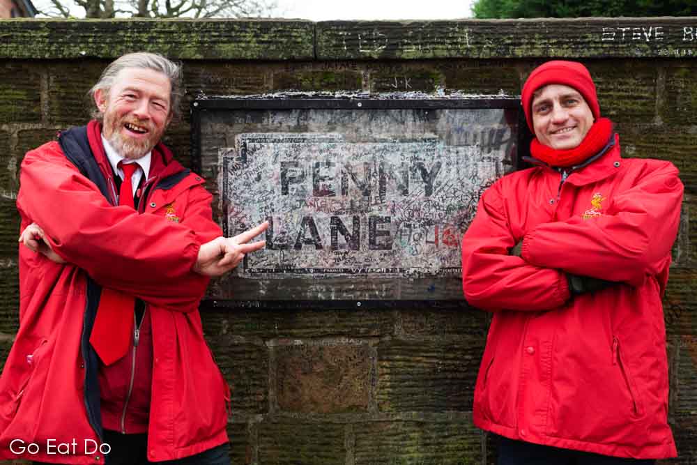 Members of the Liverpool City Sightseeing team at Penny Lane, one of The Beatles-themed stops on their guided bus tour in Liverpool, England