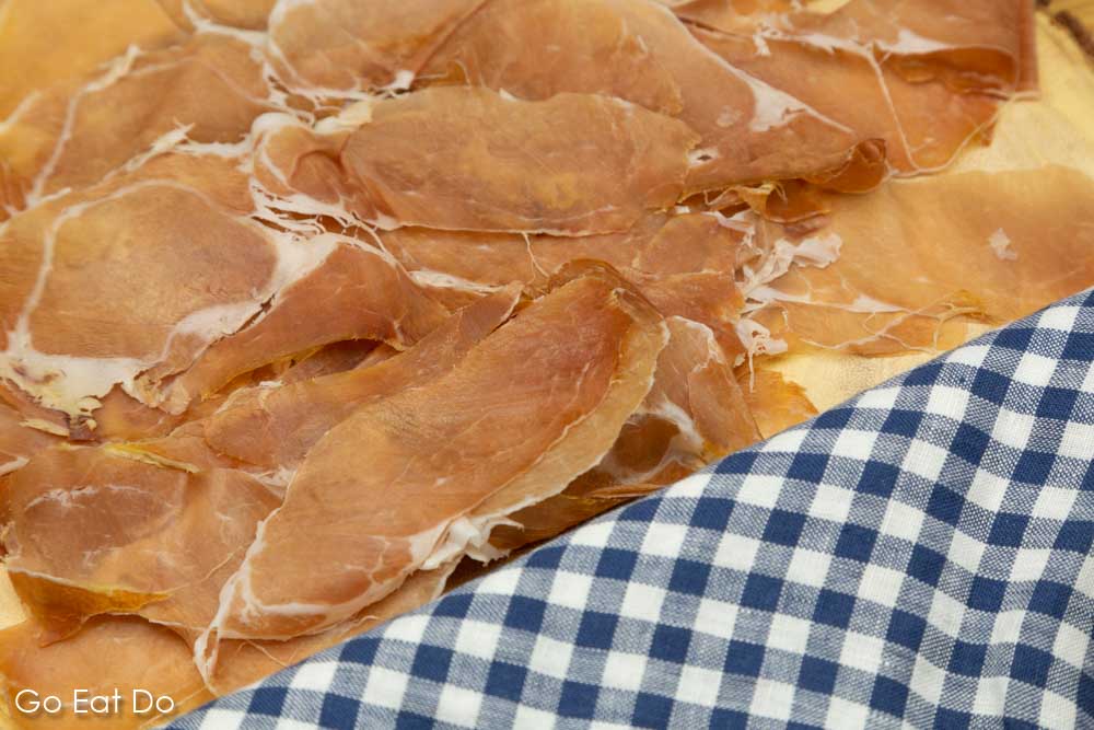 Parma ham (Prosciutto di Parma) presented on a wooden board with a checked napkin