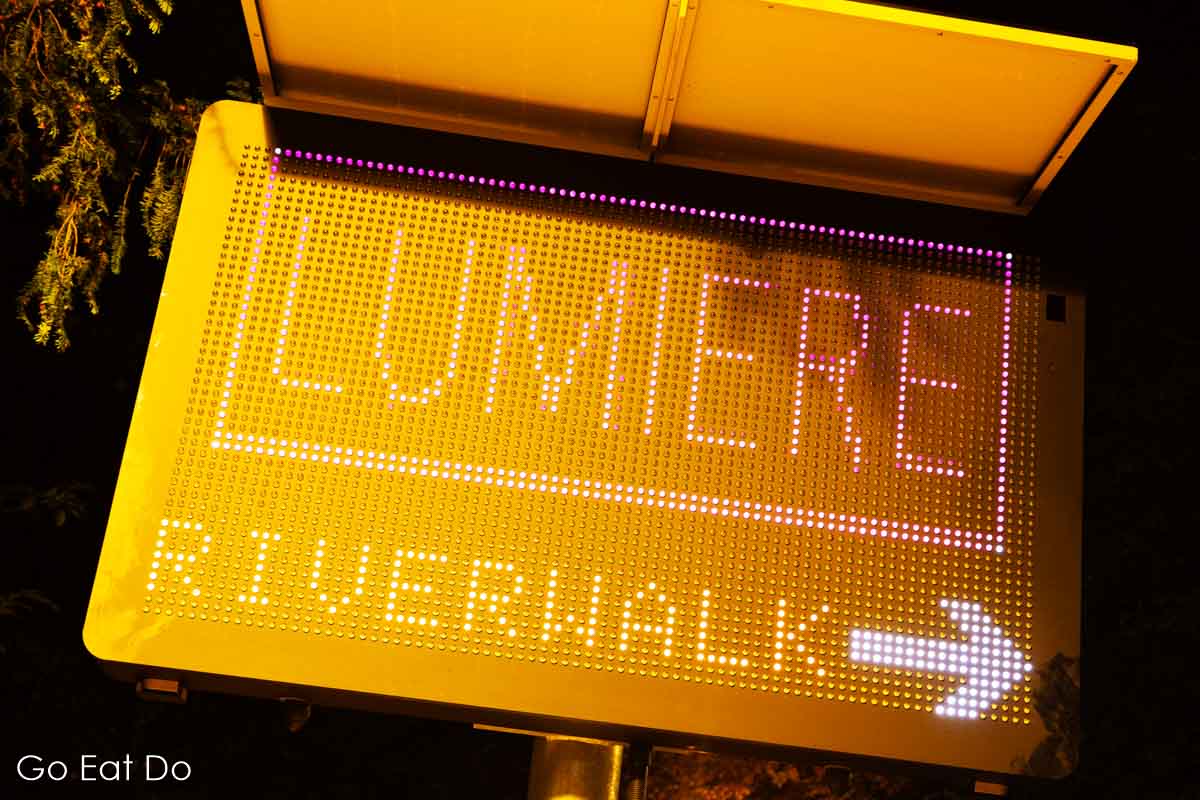 Sign pointing to the Riverwalk during the Lumiere festival of lights in Durham City.