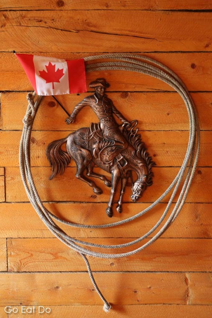 A lasso, a Canadian flag and a cowboy plaque on a wall at the ranch