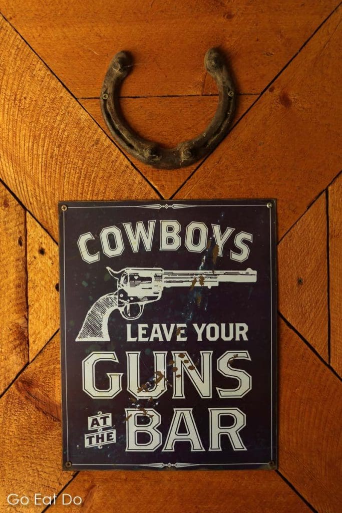 'Cowboys leave your guns at the bar' says a sign under a horseshoe