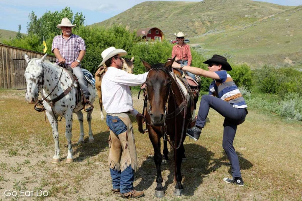 A rider mounts a horse at La Reata Ranch near Kyle, Saskatchewan