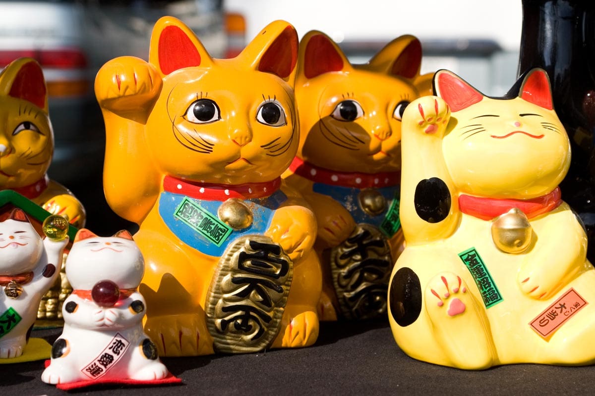 Cats with wagging arms on sale at a stall at the Kobo-san market in Kyoto, Japan