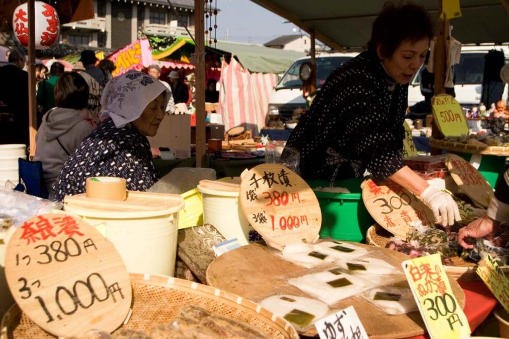Women sell traditional foodstuffs at the Kobo-san market within the precincts of the Toji Temple in Kyoto, Japan.
