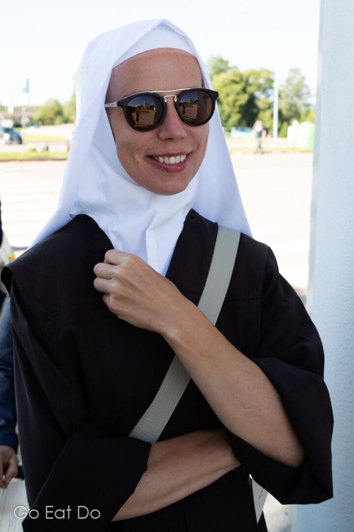 Nun by the gate of Aglona Basilica on the Feast of the Assumption of Mary