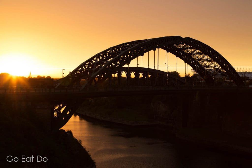 Sunset over silhouetted Wearmouth Bridge and the River Wear in Sunderland, England.