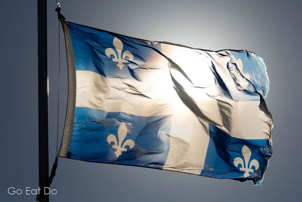 The sun shines behind the provincial flag of Quebec.