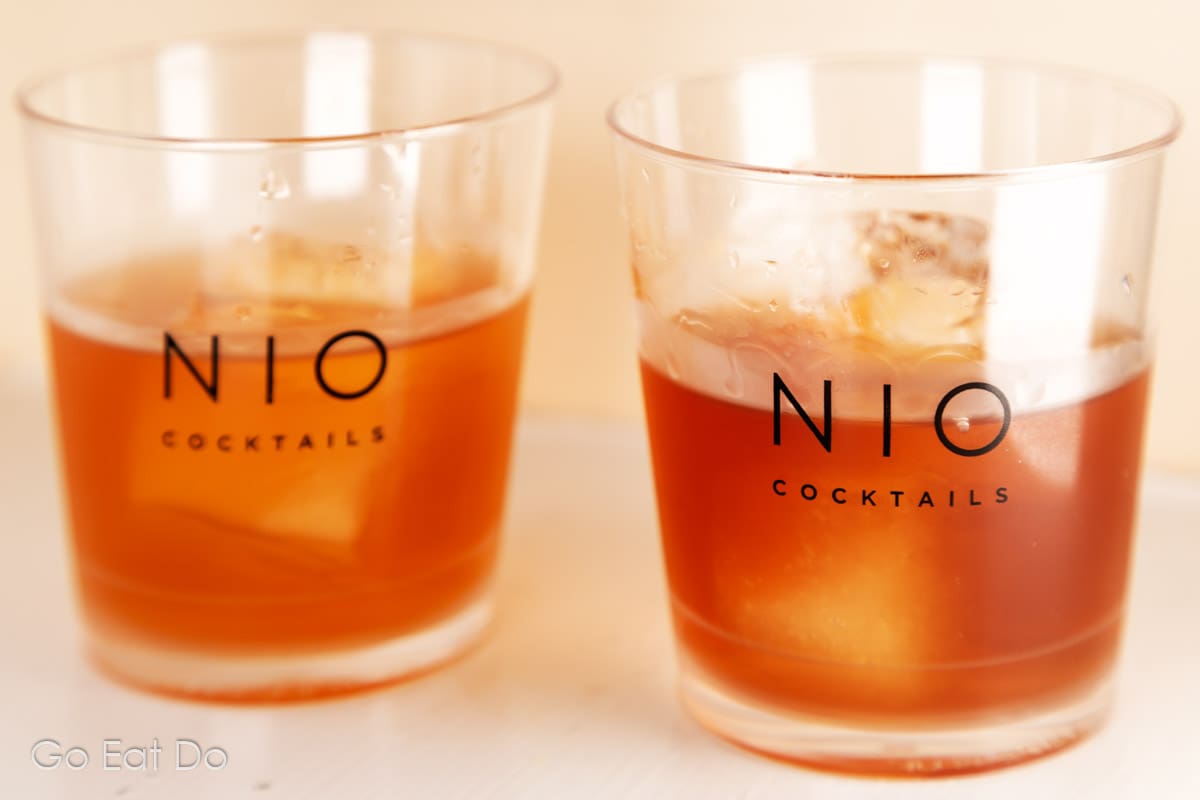 Two ready to drink cocktails served with ice in tumblers from the NIO Cocktails cocktail kit travel bag