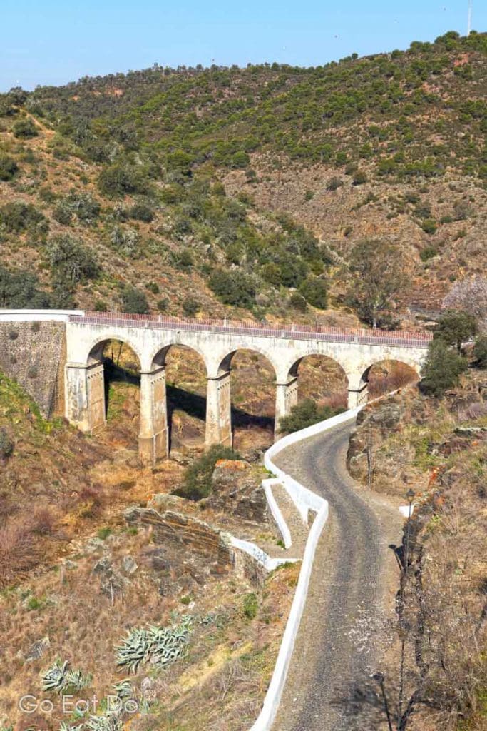 A modern bridge spans the Oeiras river at Mertola, above the ruins of a Roman-era structure.
