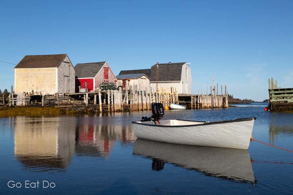 Boat by fishing shacks on a sunny day at Blue Rocks, a dishing village in Nova Scotia, Scotia.
