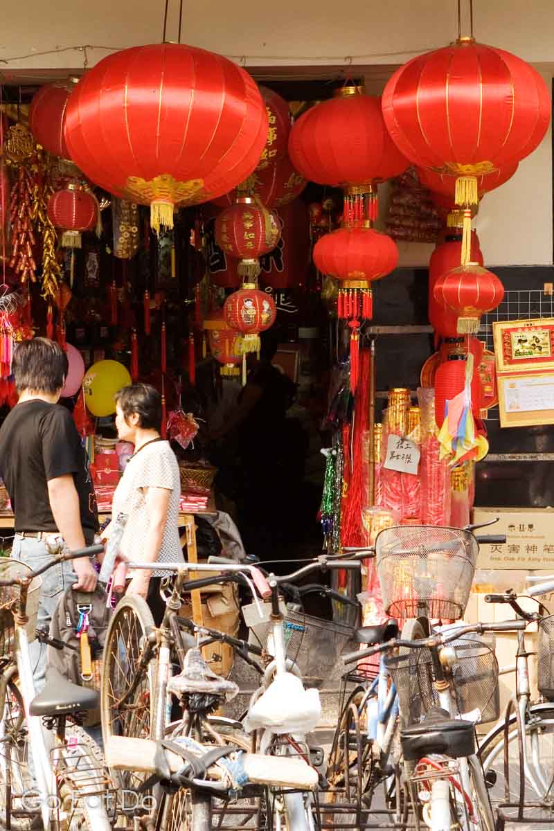 Shoppers walk past a store selling lanterns in central Shanghai. Bicycles are parked outside of the shop.