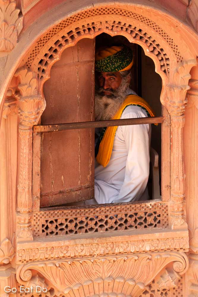A man wearing a turban looks out from one of the windows of Mehrangarh Fort. Visiting the fort counts among the top things to do in Jodhpur.