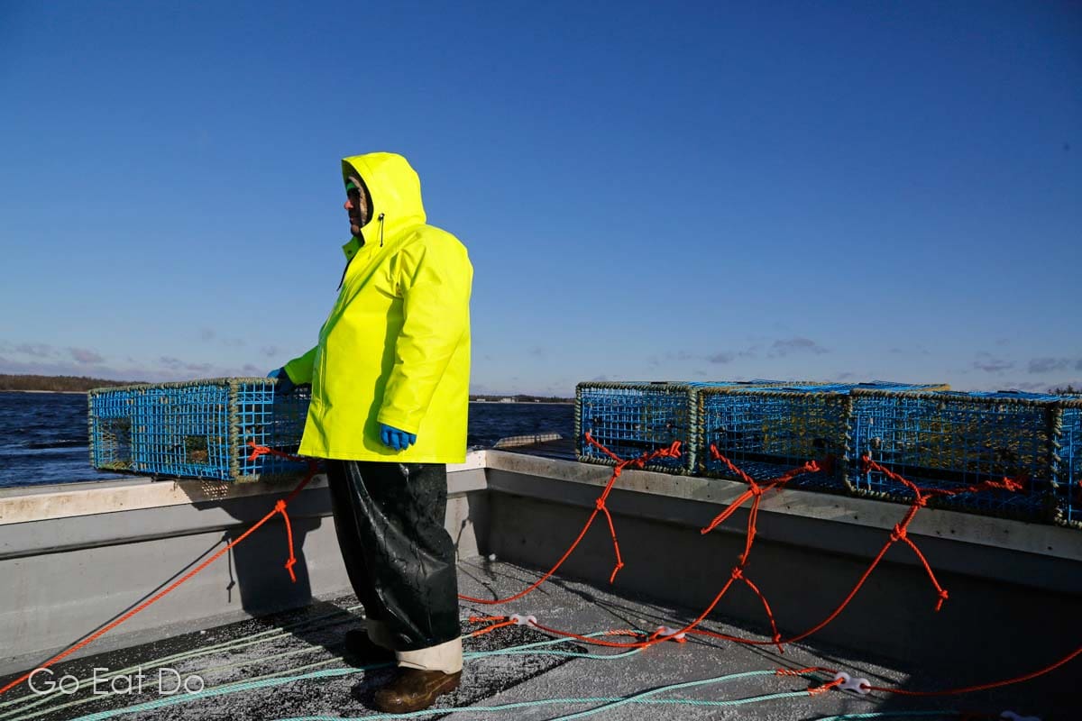 A fisherman in yellow waterproofs sets lobster traps off the coast of Nova Scotia.