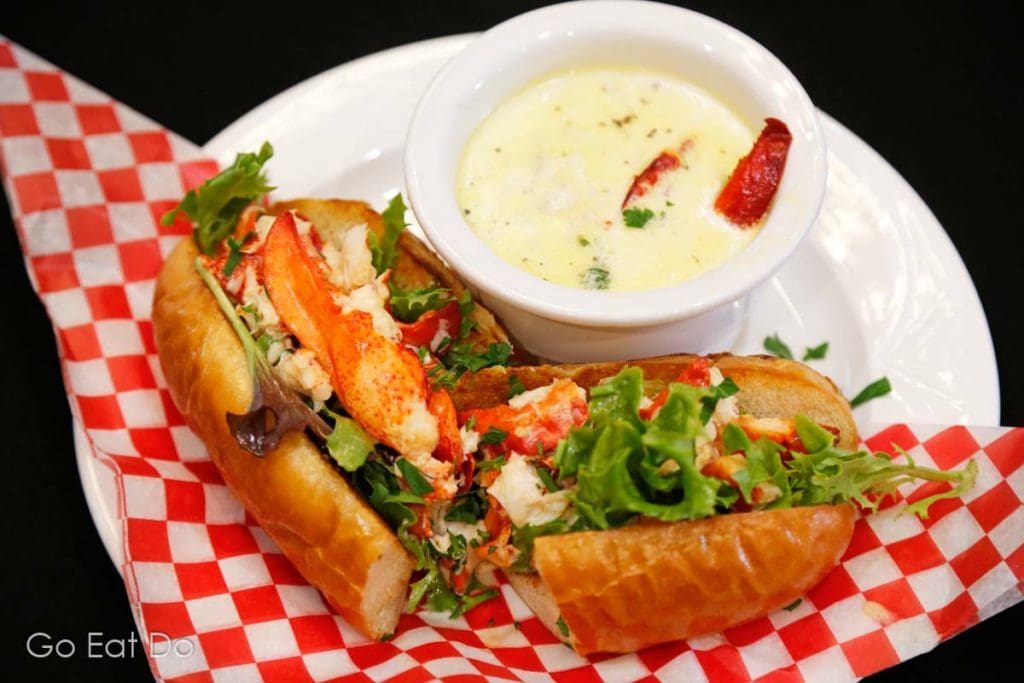 A lobster roll served with a bowl of chowder.