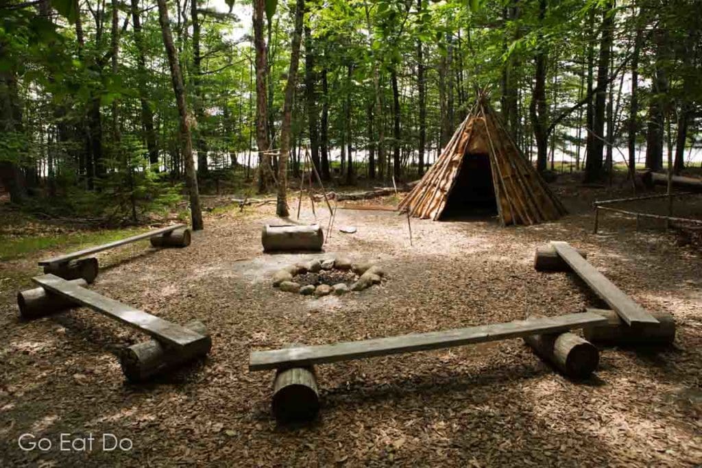 Seating around a campfire by a tipi in Kejimkujik National Park and National Historic Site where interpretive sessions offer insights into Mi’kmaq heritage.