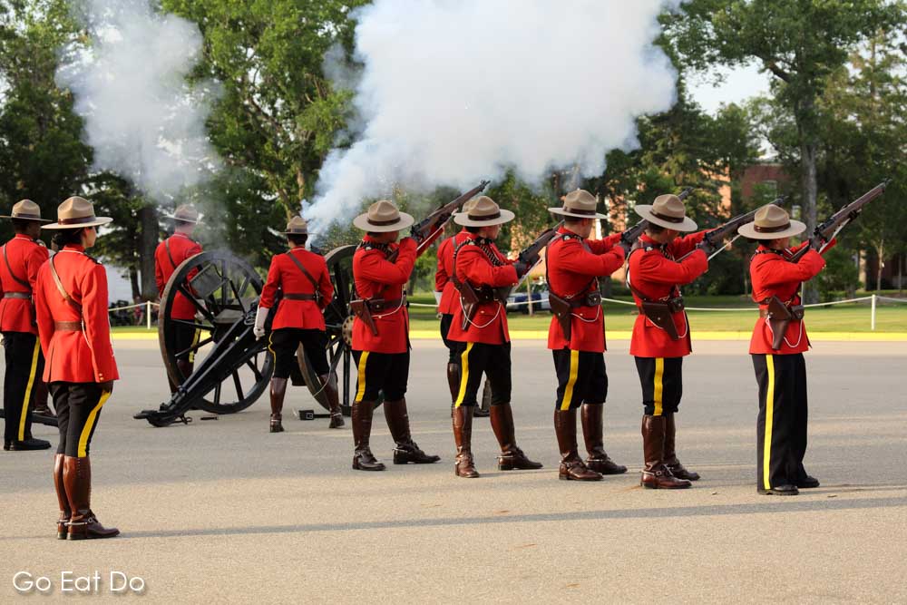 Members of the Royal Canadian Mounted Police firing rifles and a field gun during the Sunset Retreat Ceremony in Regina.