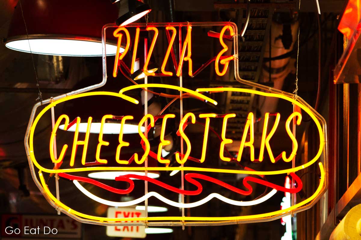 Neon sign for pizza and cheesesteaks at Reading Terminal Market in Philadelphia, Pennsylvania.