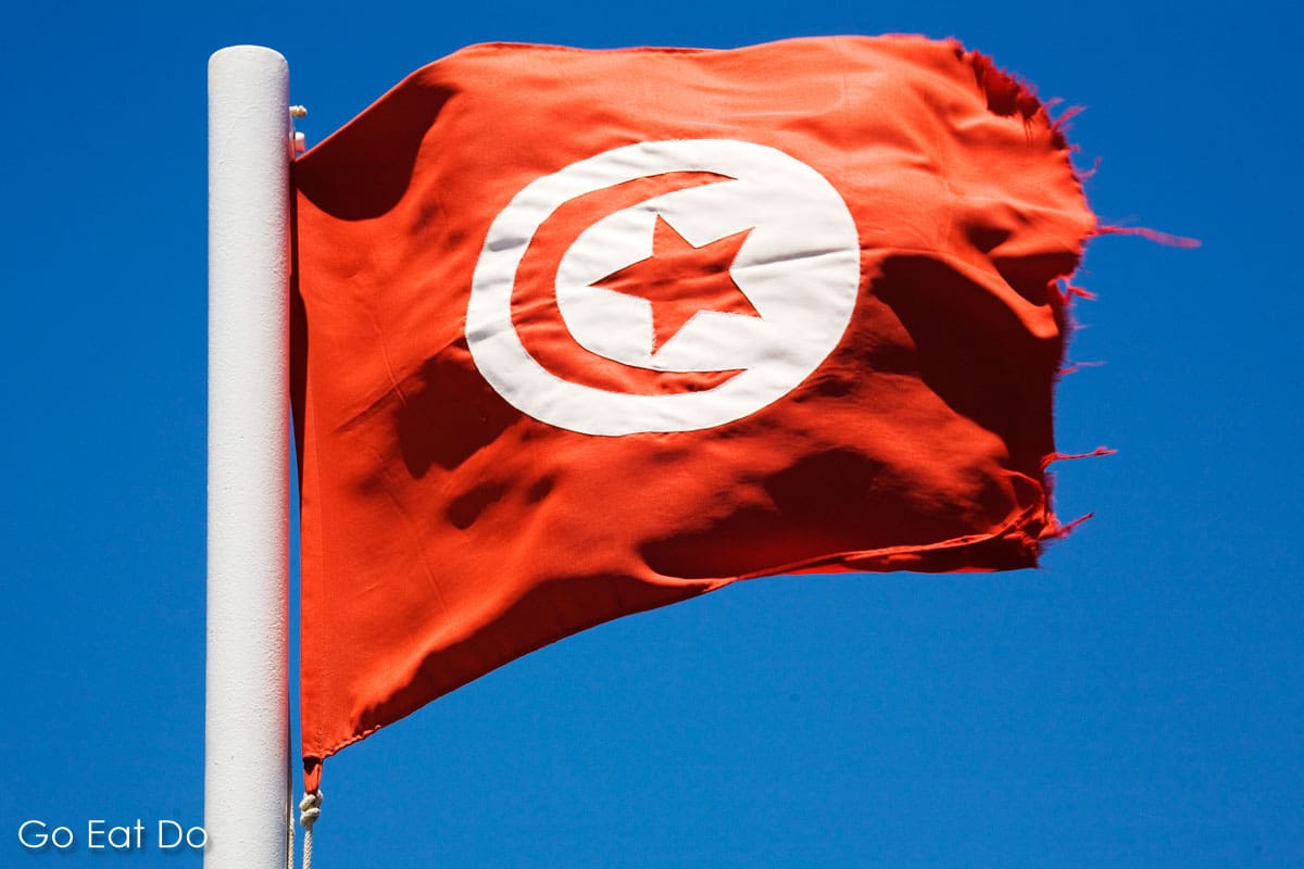 Flag of Tunisia fluttering on a sunny day in a blue sky