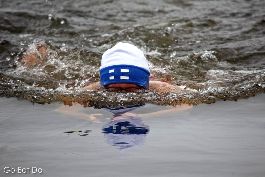 A man in a hat bearing the flag of Finland winter swimming in Lake Pyhäjärvi.