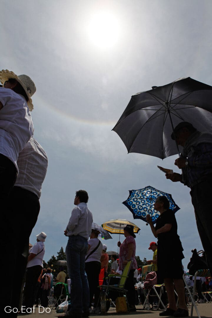 Christian pilgrims hold umbrellas to provide shade from the sun while a solar halo flares around the sun in Fatima, Portugal, on 13 May 2011.