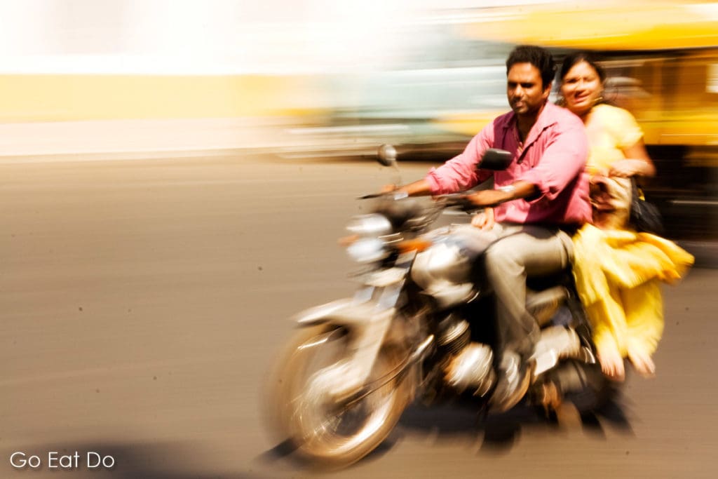 Man and woman on a motorbike on a road in Goa, India.